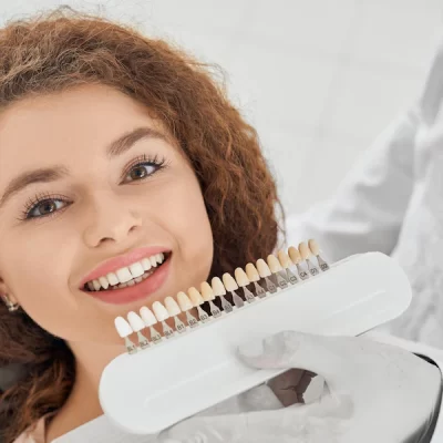 mulher-sorrindo-enquanto-dentista-masculino-mantendo-a-gama-de-cores-dos-dentes_651396-1397